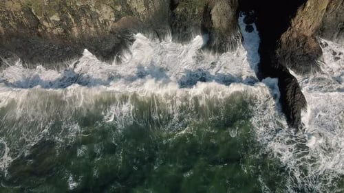 Vue aérienne au Ralenti d'une vague de marée royale claquant une falaise rocheuse de la côte