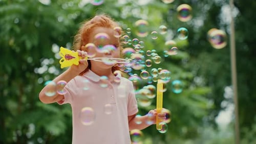 Young Girl Blows Colorful Bubbles in the Park on a Sunny Afternoon