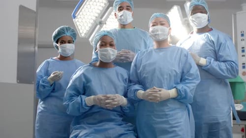 Portrait of diverse surgeons wearing surgical gowns in operating theatre, slow motion