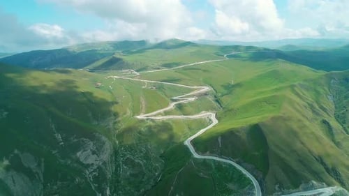 Aerial Over Winding Asphalt Road Among Mountains Covered with Green Grass in Highlands of Caucasus