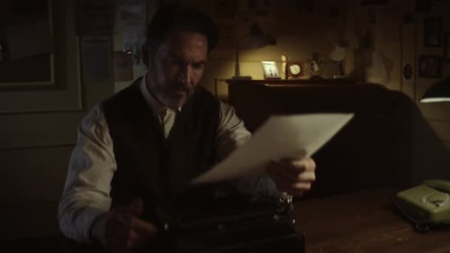 Author typing on typewriter and reading notes in dimly lit room