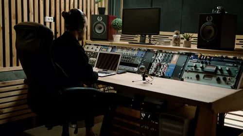 young sound engineer with headphones working in a music studio with monitors and an equalizer