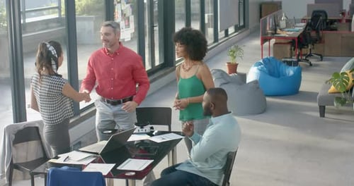 Team of diverse colleagues shaking hands with each other at office