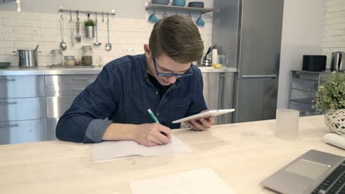 Teen Boy Studying Using Tablet and Notebook