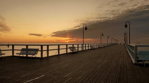 Slowly floating over a wooden pier. Orange sky at sunrise at the seaside. Aerial footage on the empt