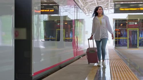Young Woman on Empty Platform of Suburban Railway Station Rolling Her Suitcase Behind Herself