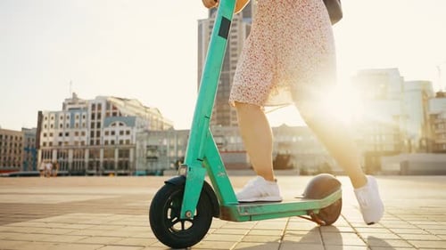 Junge Frau auf einem Elektroroller macht lustige Fahrten durch die Straßen der Stadt