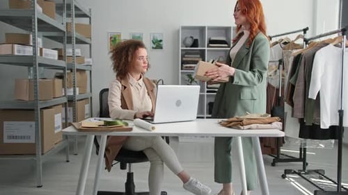 Young Female Salesperson Processes Internet Orders in Clothing Store Online and Makes Purchases for
