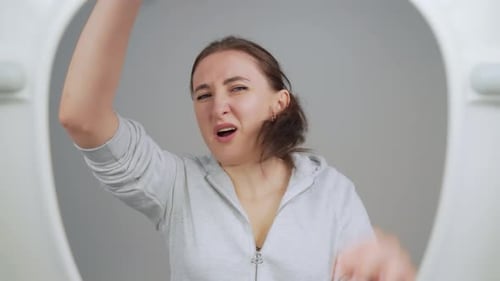 Distressed Woman Looks in Toilet Bowl in Disappointment