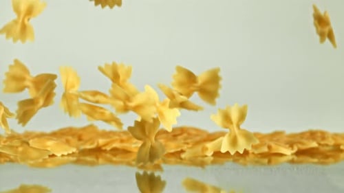 Farfalle pasta falling on reflective surface, food concept
