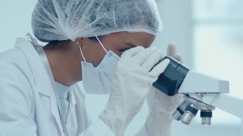 Female Lab Worker in Protective Medical Uniform Using Microscope