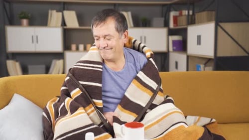 Man Under Blanket Sitting on Sofa Feeling Unwell
