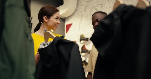 Exploring Outdoor Attire European Girl and Black Guy Browse Hiking Clothing in Store