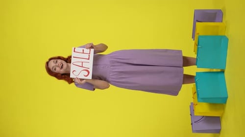 Smiling Woman Holds Sale Sign with Shopping Bags