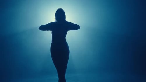 Silhouette d'une femme gracieuse dansant en rétroéclairage bleu