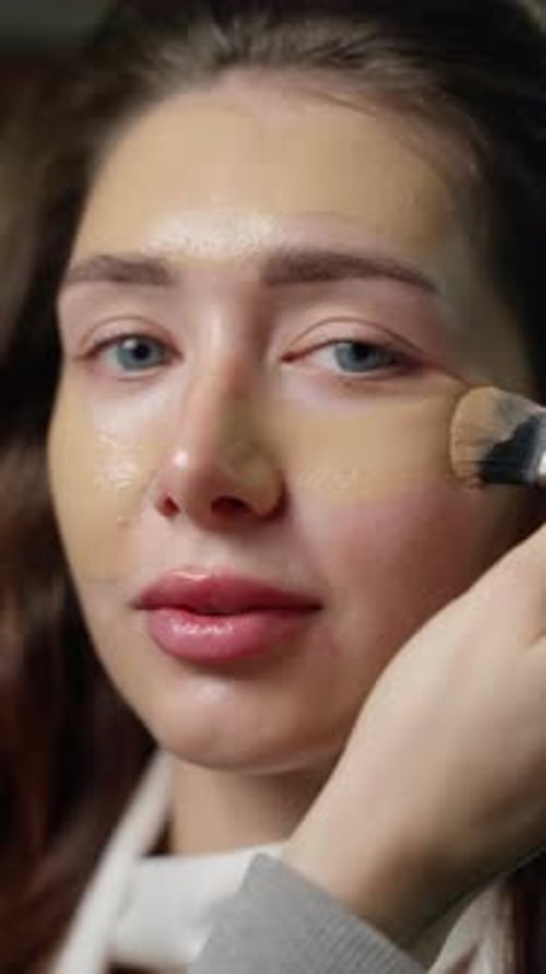 Professional Makeup Artist Applying Foundation on Model with Specialized Brush Demonstrating Precise