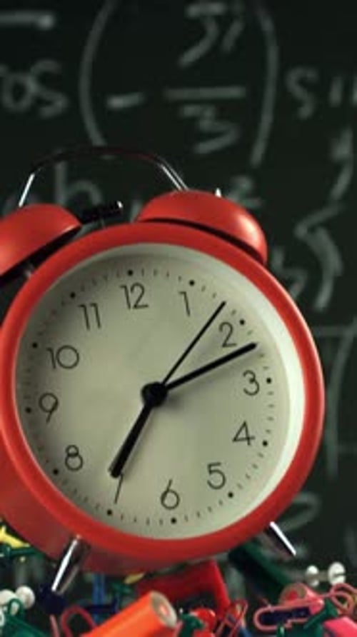 Alarm Clock and School Tools Soaring Up Against the Blackboard Background Filmed on a Highspeed