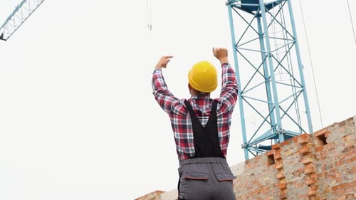 Gestionnaire sérieux portant un casque et un uniforme donnant des ordres au grutier