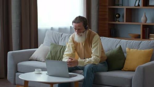Senior Man Video Conferencing on Laptop in Living Room