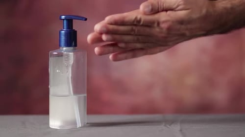 Covid-19 virus prevention adult male sanitizing hands with Alcohol Based Hand Rub liquid gel - close