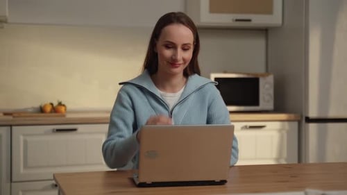 Woman Opens Laptop in Kitchen