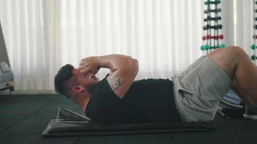 Plan latéral d'un jeune homme fort faisant des crunches dans la salle de sport
