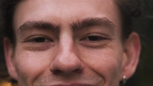 Close Up Portrait of Young Man Opens His Eyes and Stares Into Camera Outdoor