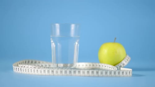 Glass of Apple Fresh Water Green Apple and Measuring Tape Over Blue Background