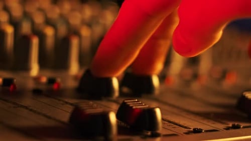 Hand Settings Volume Level Controls on Mixing Console Faders Neon Light CloseUp