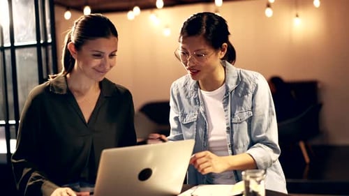Two Women Collaborating on Laptop in Office