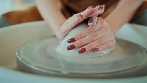 Close up hands of artisan's shaping creating clay bowl in pottery wheel in studio