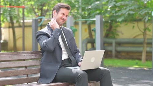 Man Types on Laptop, Rubs Sore Neck Outdoors