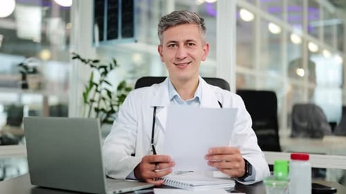A Confident Doctor in a White Lab Coat Smiling in a Modern Medical Office