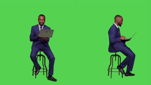 Young Man in Suit Talking with Laptop on Greenscreen