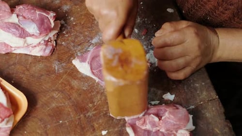 closeup female hands beating raw fresh meat with a wooden mallet, concept of cooking steak chops in