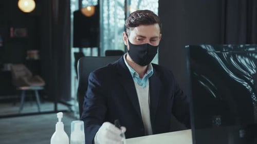 Masked Man Sanitizes Hands in Modern Office