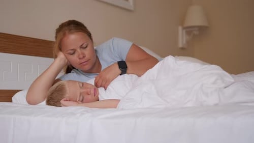 A Little Boy Sleeps in Bed in the Morning His Mother Hugs Him Carefully