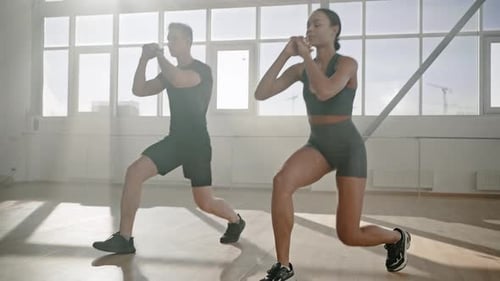 Slow Motion Attractive Confident Determined Couple Squatting and Doing Lunges During Morning Workout