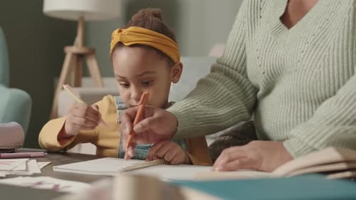 Child Drawing with Adult Helper in Home