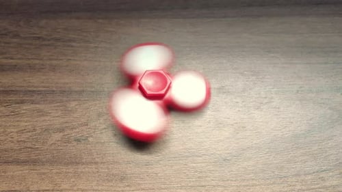 homme blanc faisant tourner un fidget spinner sur une table