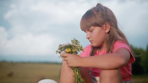Young Girl with Wildflowers Sitting in Green Field