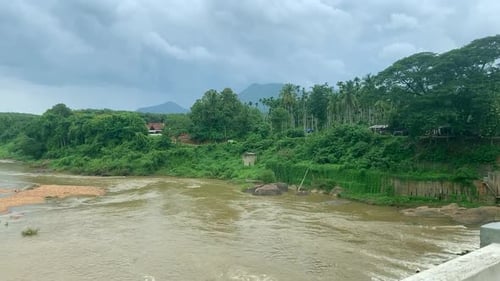 a beautiful scenery of a lake flowing after a rain in Kerala with mountains and greeneries in the ba