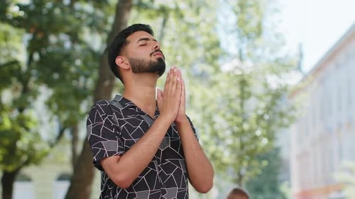 Young Man Prays in Urban Park Setting