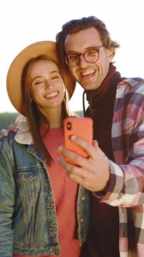Shot at Sunlight Young Smiling Couple Use Phone and Take Selfie in the Forest Near Lake Nature