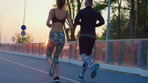 Couple Jogging at Sunset on City Path
