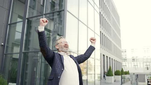 Excited Businessman Raising Arms in Front of Office Building