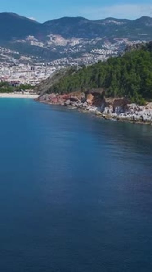 Vertical Video of a Stunning Rocky Coastline Framed By Lush Green Trees and CrystalClear Azure Water
