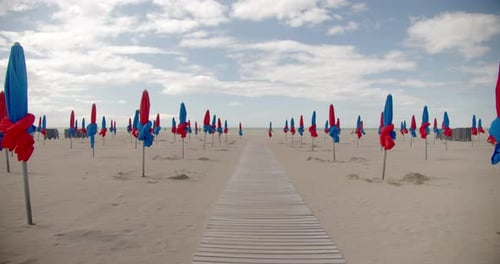 Endless wooden pathway in sandy beach with closed umbrellas. Empty beach
