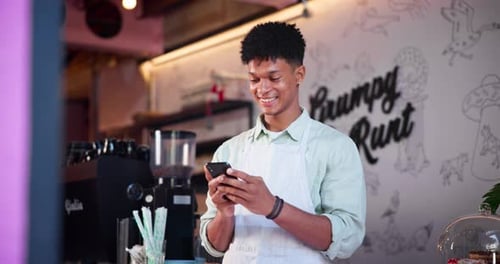 Smiling Man Typing on Phone in Bakery