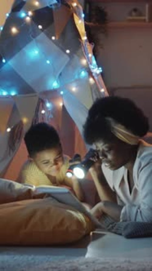 Child and Adult Reading in Tent with Flashlight